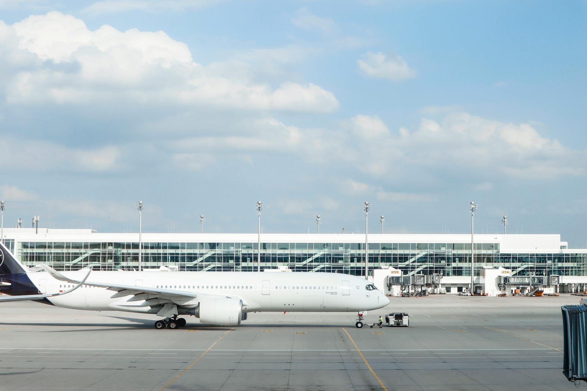 Widebody aircraft parked at an airport gate during clear day with terminal building visible.