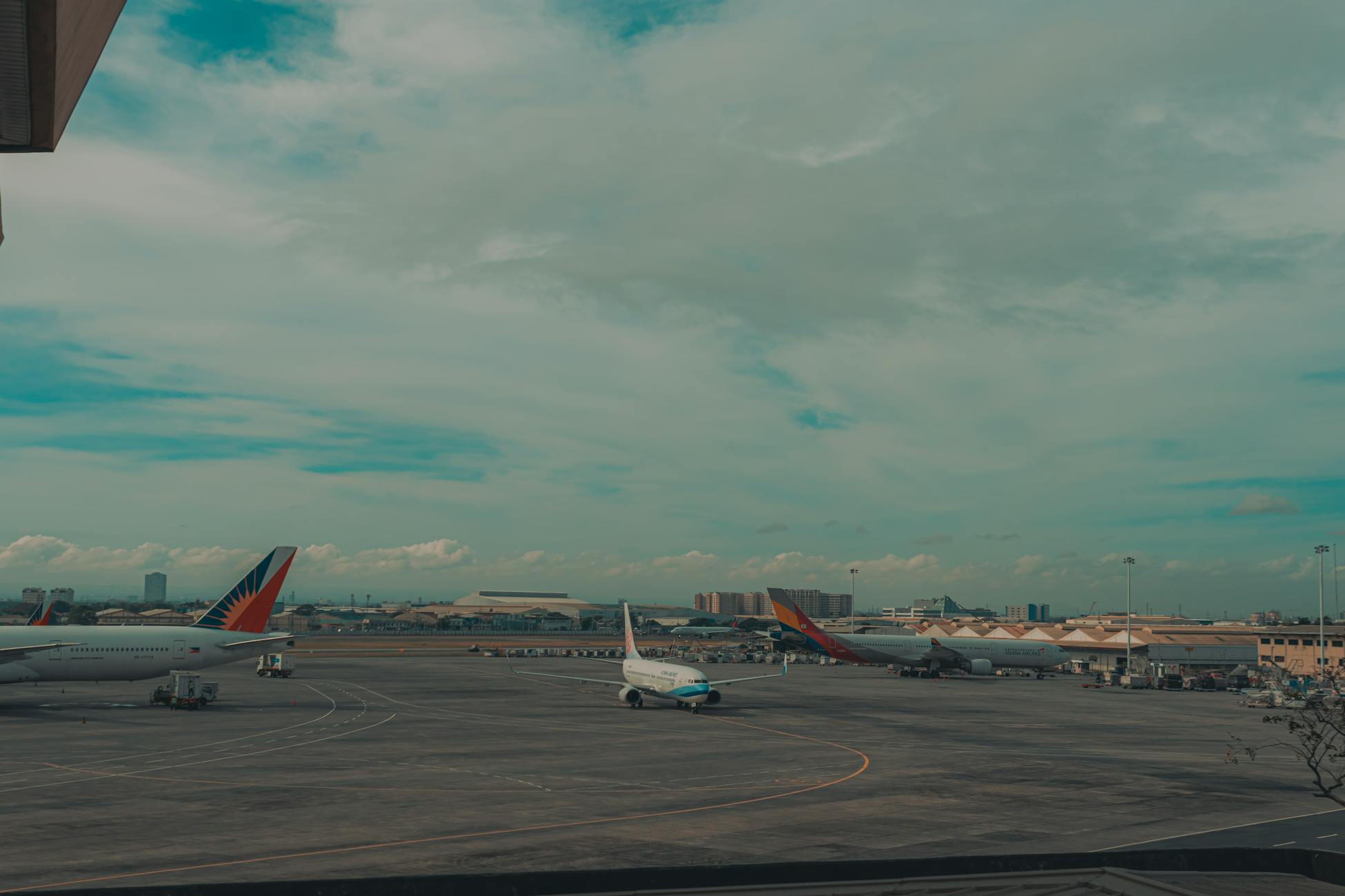 Wide view of airplanes parked at an airport next to a city skyline under a vast sky.