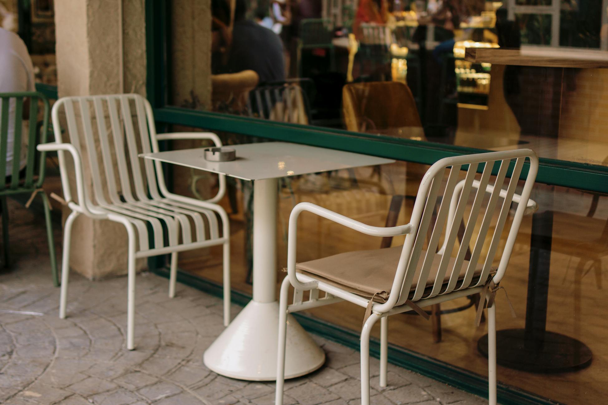 Empty metal chairs and table outside a café, reflecting an inviting ambiance.