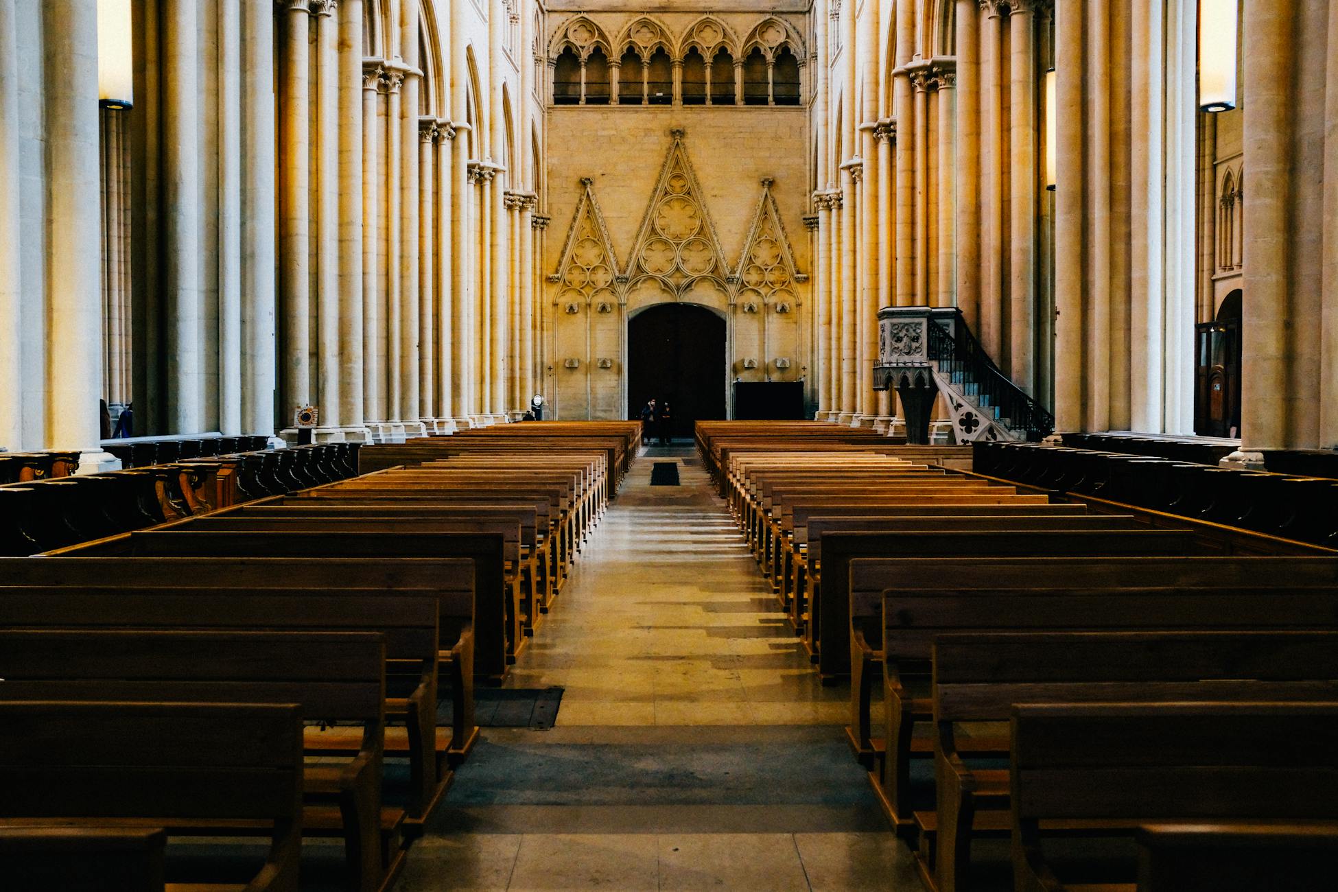 Empty pews in a Gothic cathedral interior, showcasing majestic columns and arches.