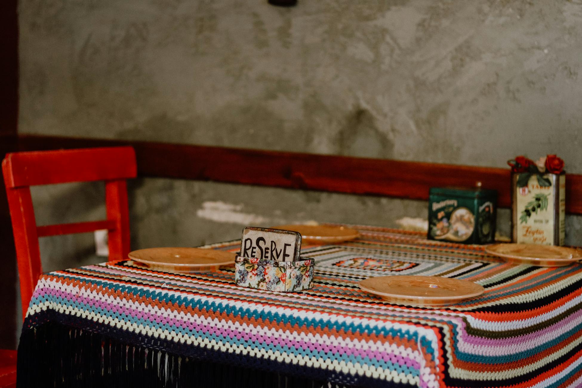 Vibrant restaurant table adorned with a colorful weaved tablecloth, set for dining with reserve sign.