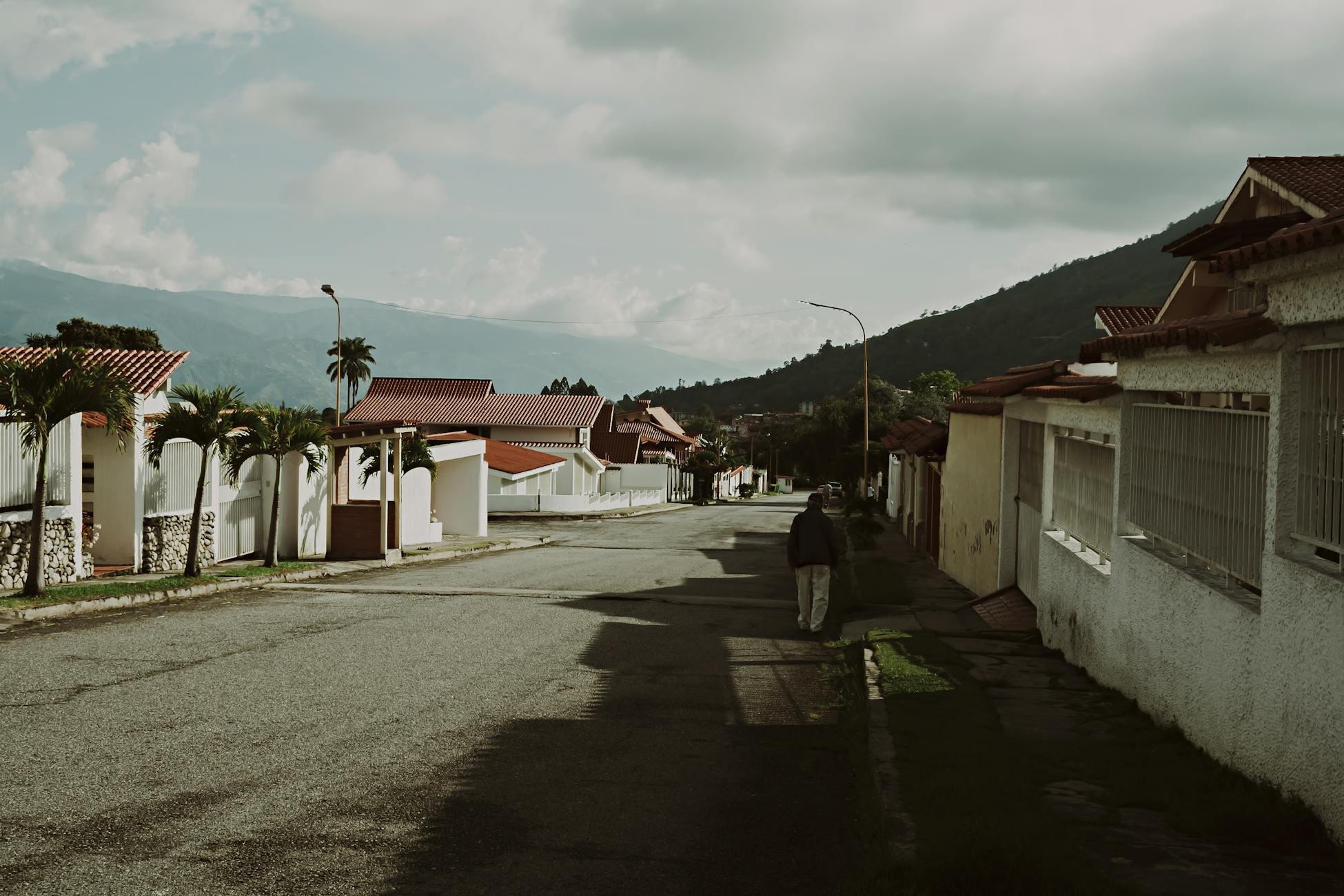 Quiet suburban street in Mérida, Venezuela, featuring tile-roofed houses and mountain views.