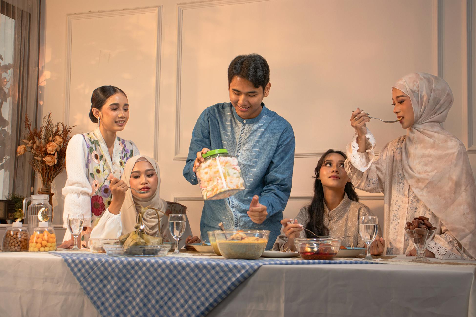 A group of adults enjoying a festive meal indoors with traditional attire in Indonesia.