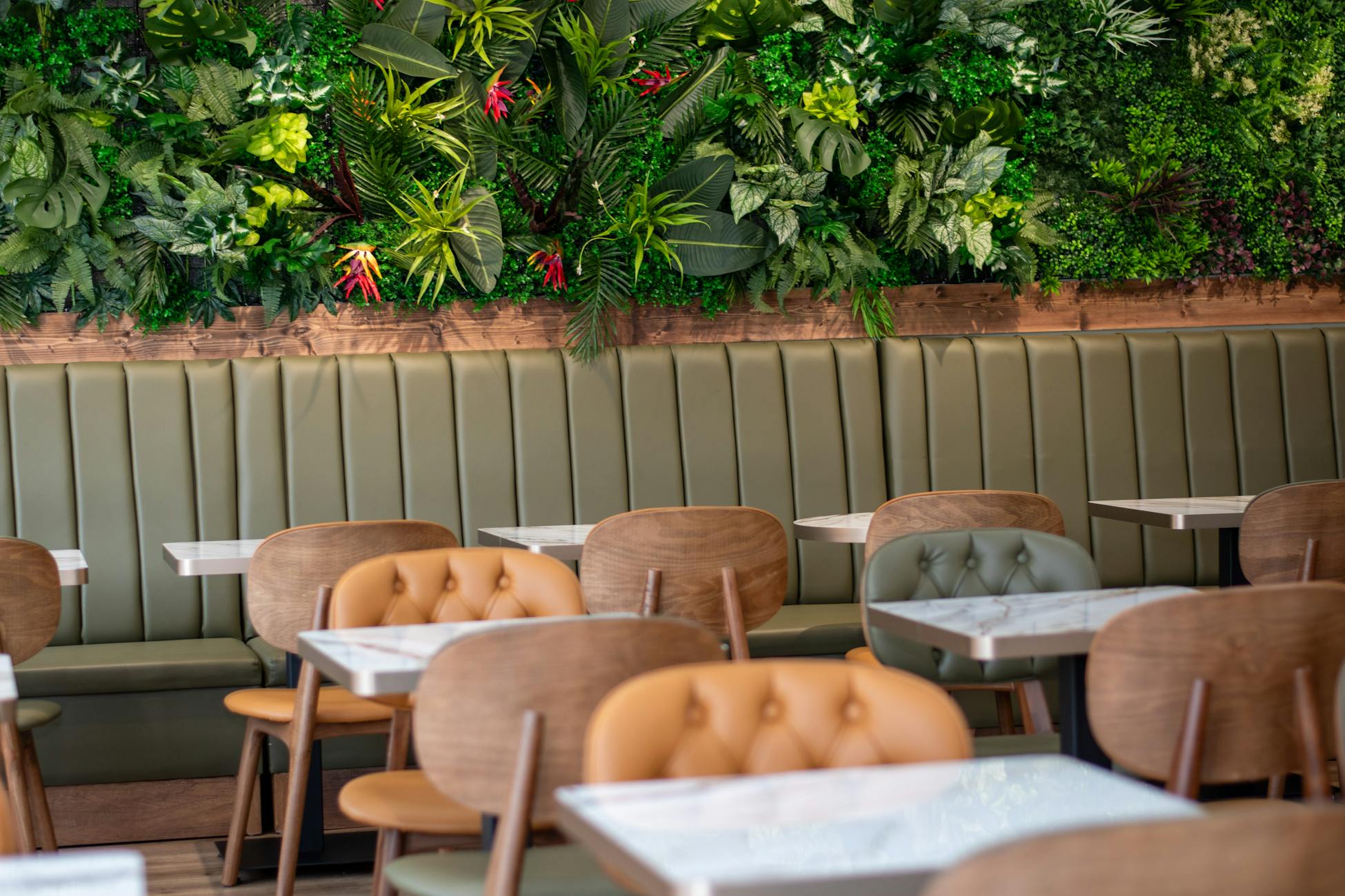 A modern cafe interior with elegant seating and a vibrant green wall, creating a relaxing ambience.
