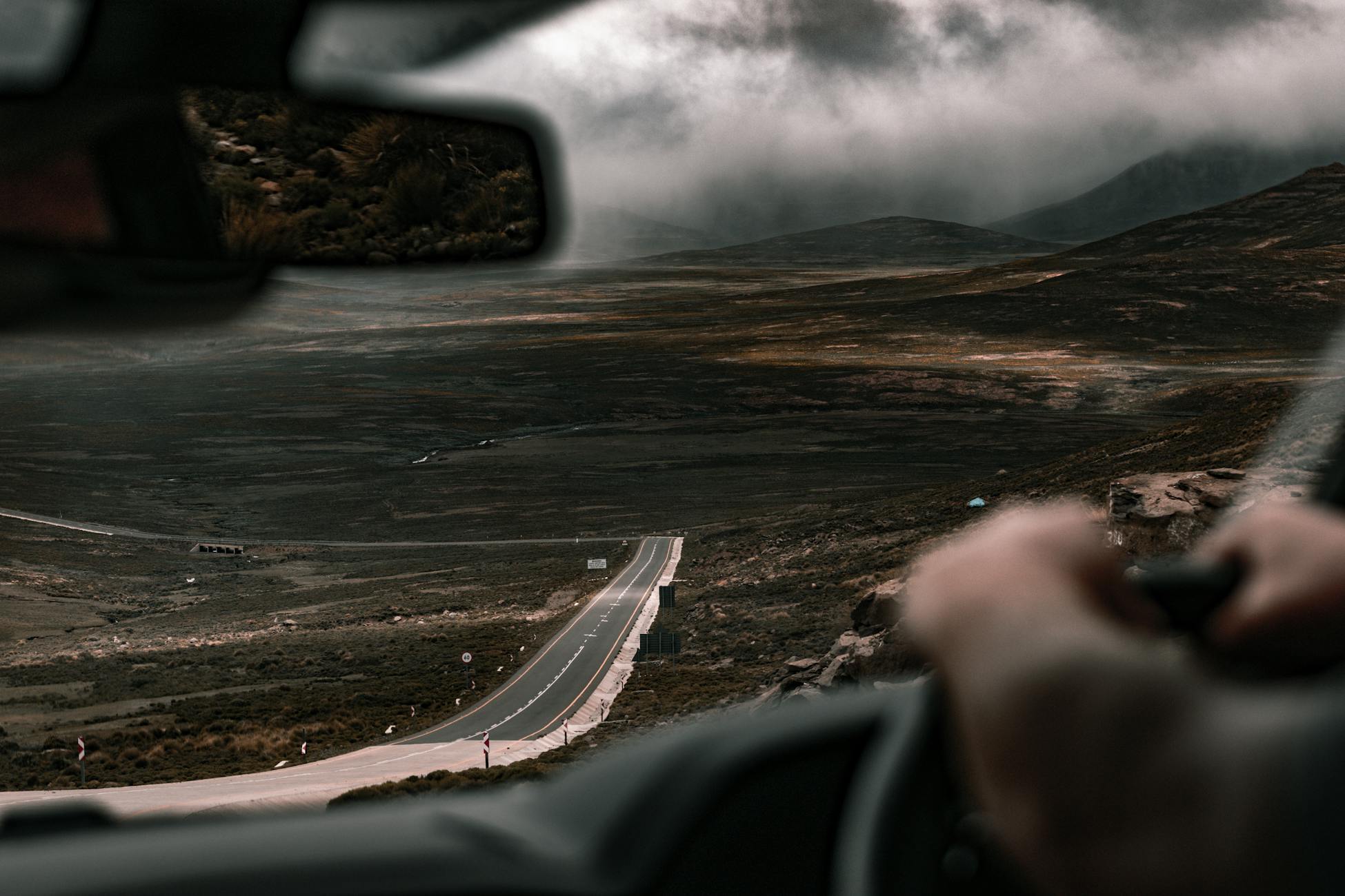 Scenic view from a car on a tranquil country road surrounded by foggy hills.