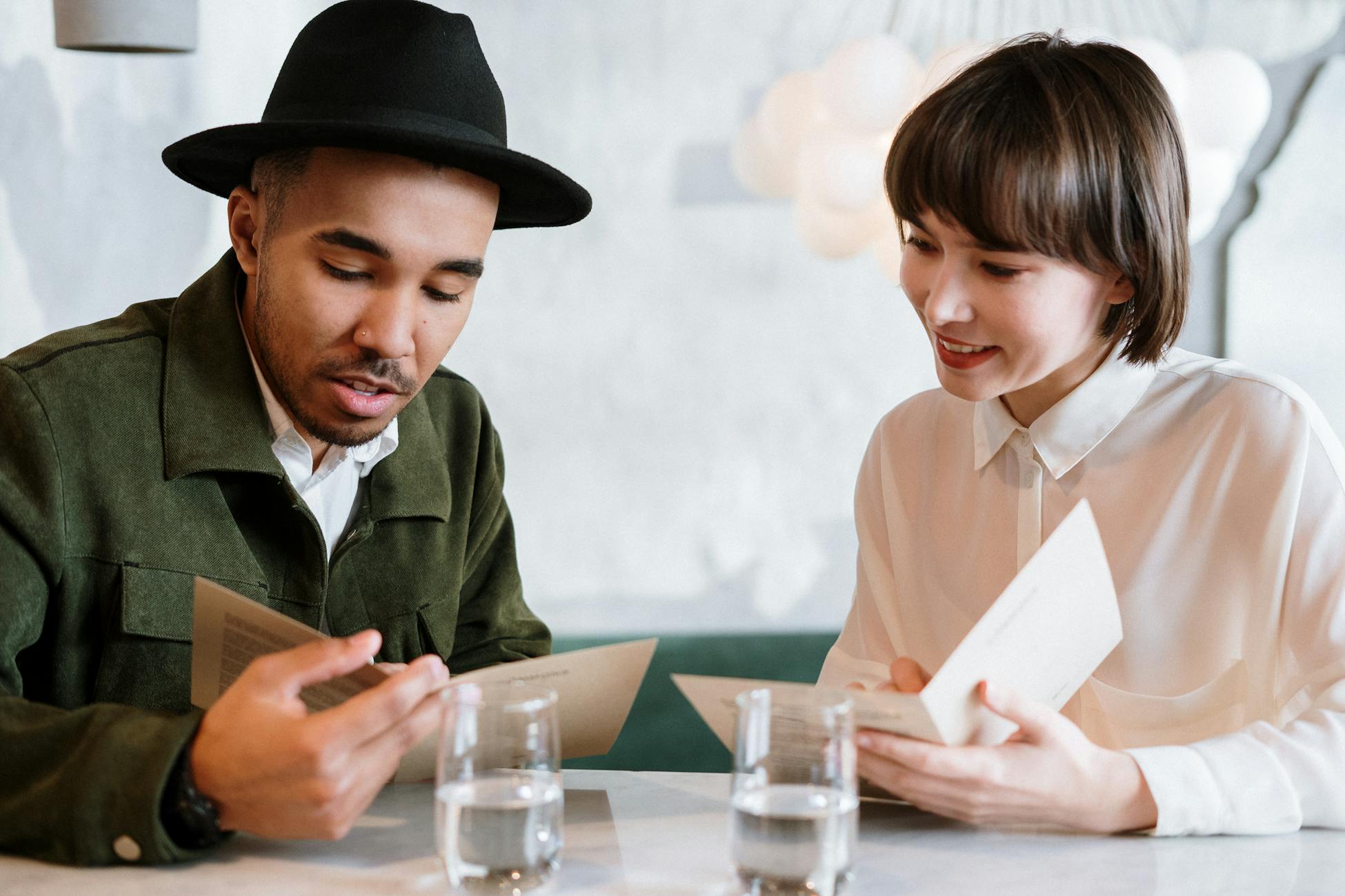 A couple sitting at a café table browsing menus together.
