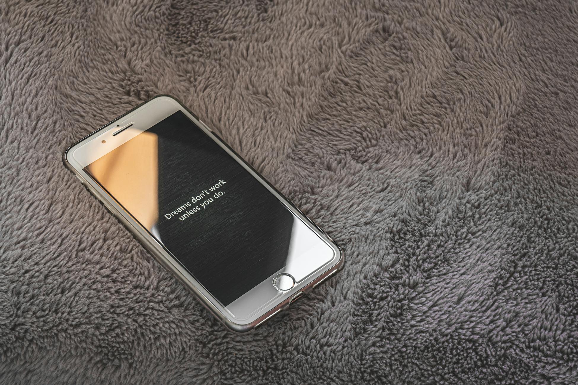 A smartphone displaying an inspirational quote on a cozy gray blanket, perfect for themes of motivation and relaxation.