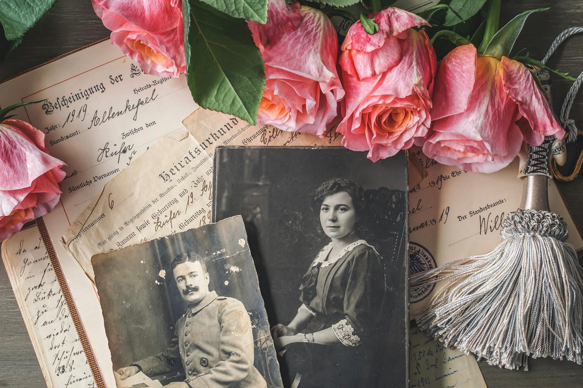 Antique family photographs with pink roses and historic documents.