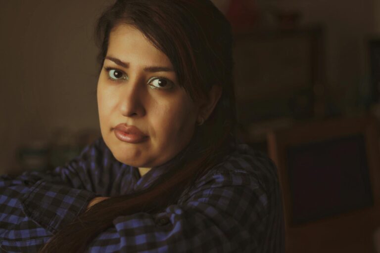 Portrait of a thoughtful woman indoors wearing a plaid blouse, conveying a pensive mood.