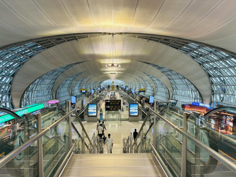 Futuristic architecture of Suvarnabhumi Airport, Bangkok, bustling with travelers.
