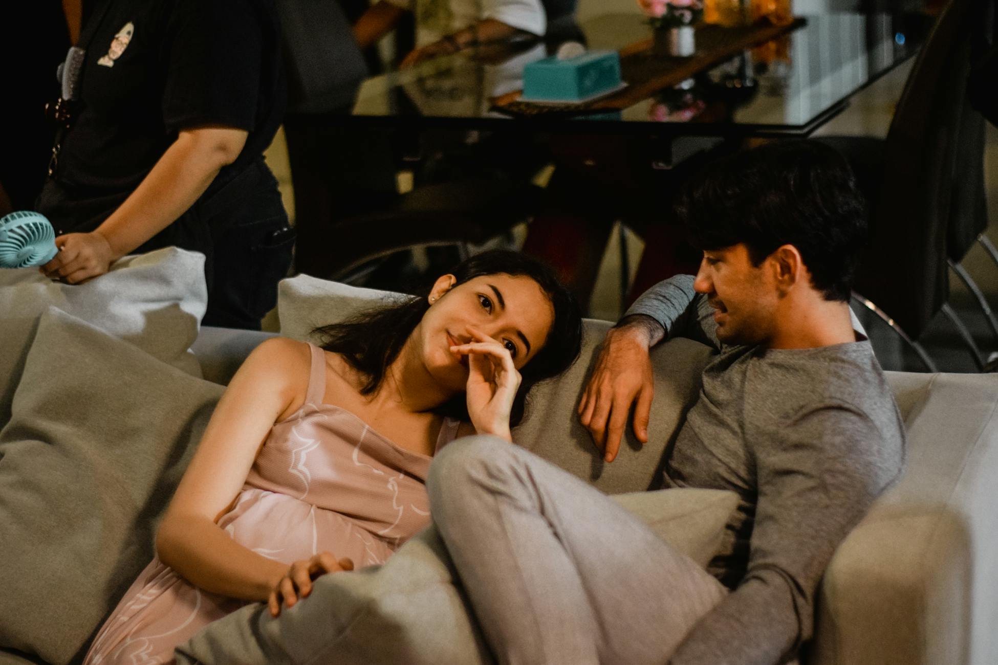 A couple sharing a moment of affection lounging comfortably on a sofa indoors.