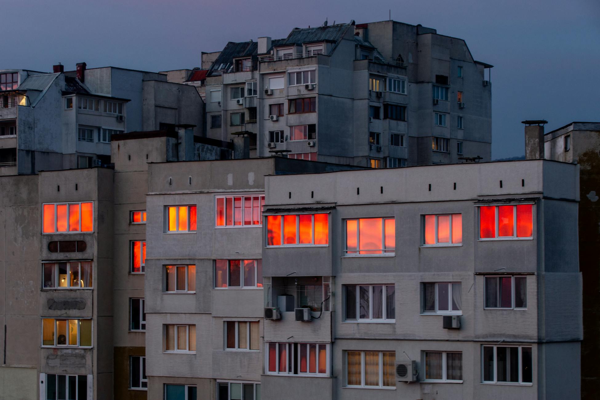 Sunset light reflects on urban apartment building windows, creating a dramatic effect.