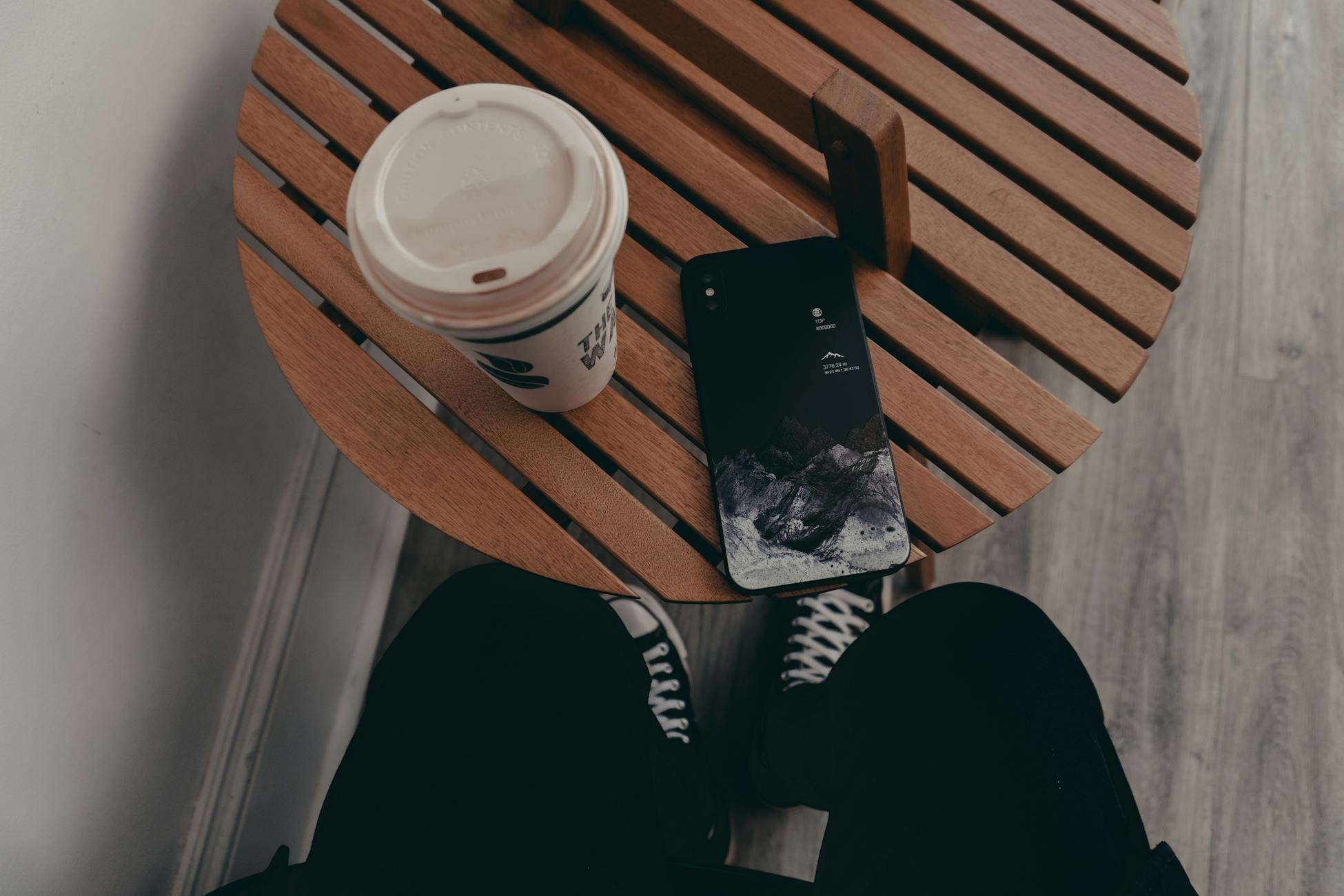 Cozy indoor setting with a coffee cup and smartphone on a round wooden table.