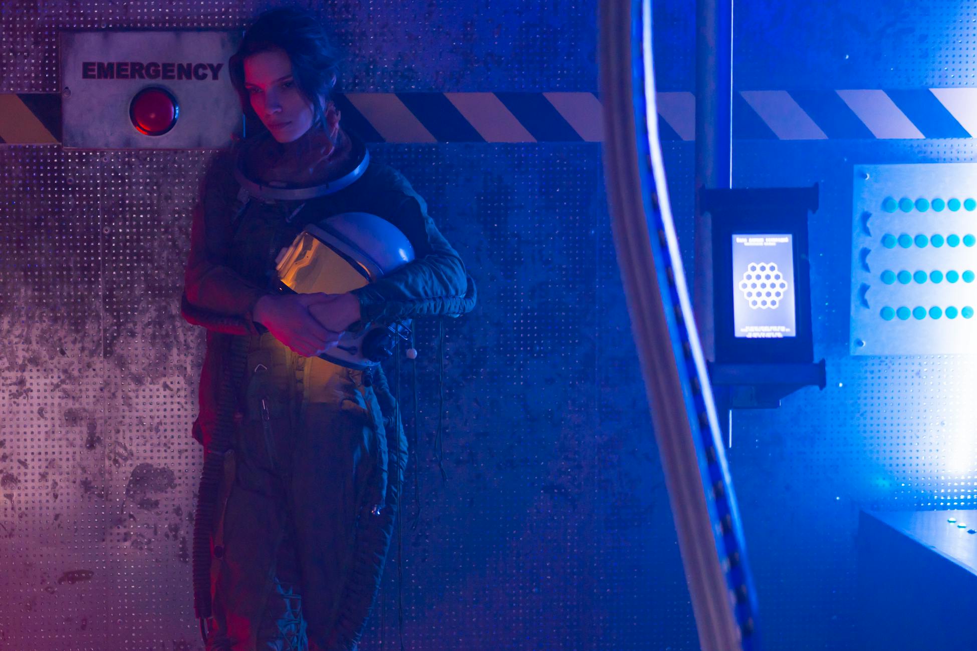 A woman in a spacesuit stands inside a spacecraft, highlighting space exploration themes.