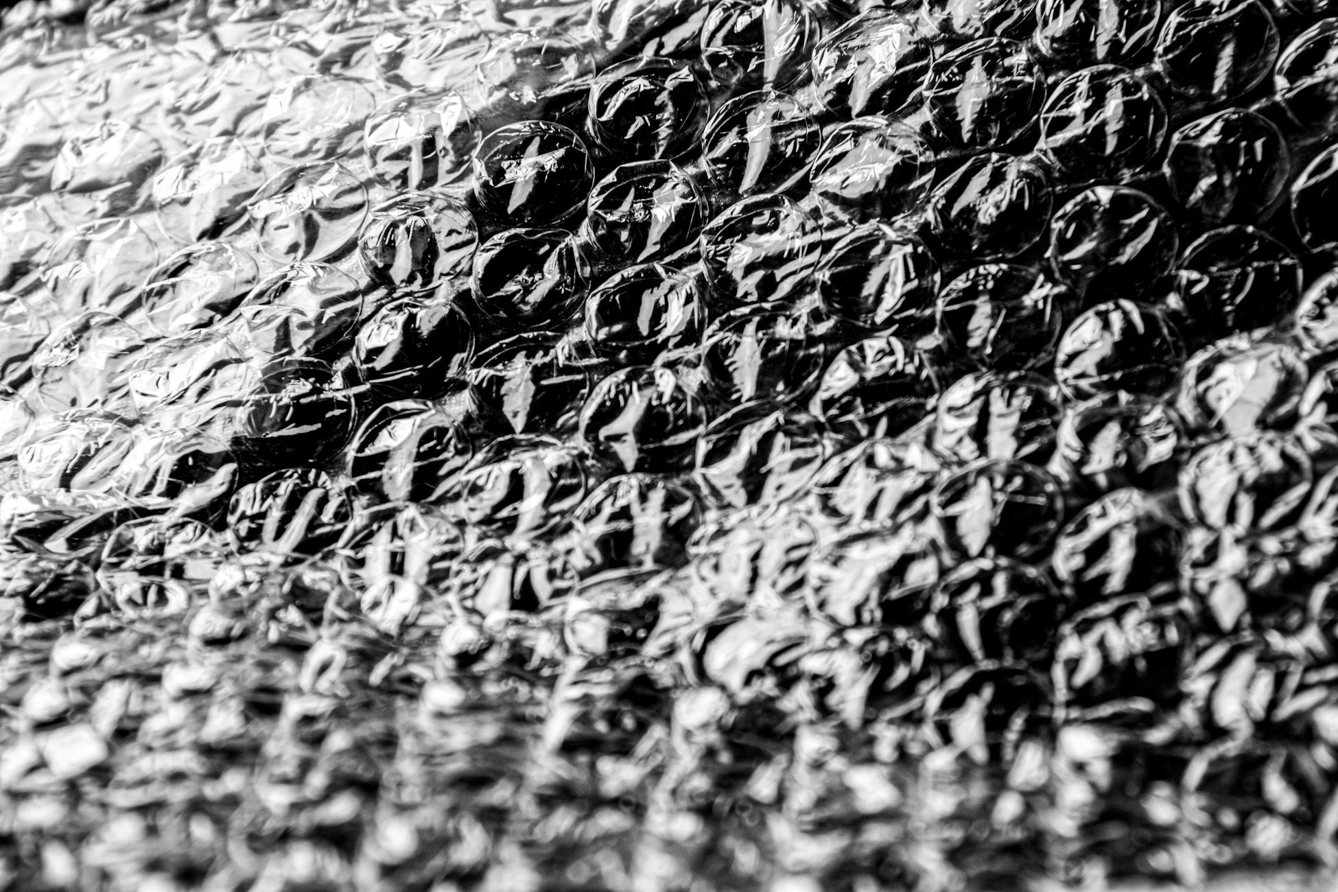 Detailed black-and-white close-up of bubble wrap texture, capturing its intricate pattern.