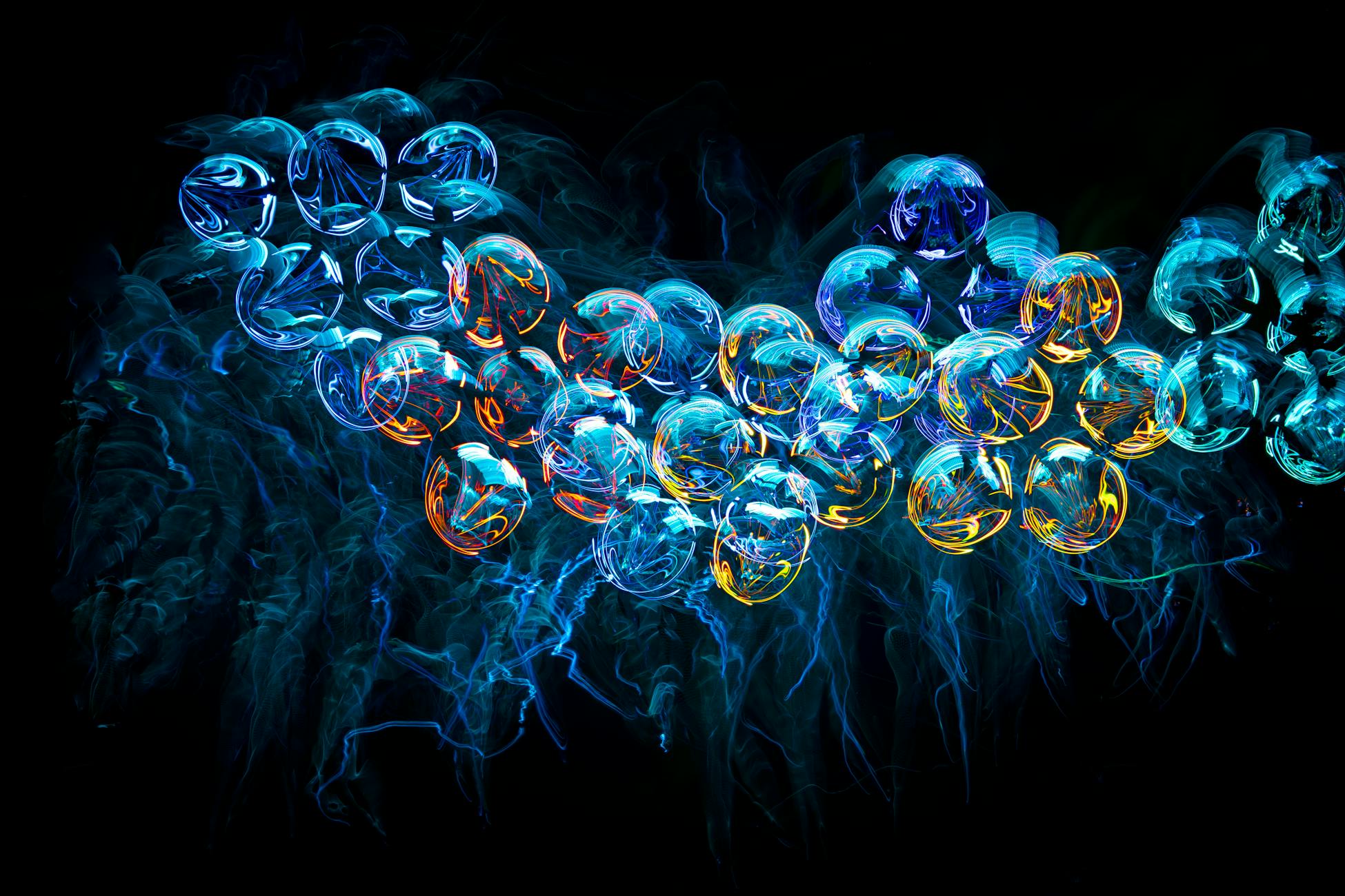Colorful abstract neon jellyfish-like shapes with a futuristic and illuminated fractal design on a black background.