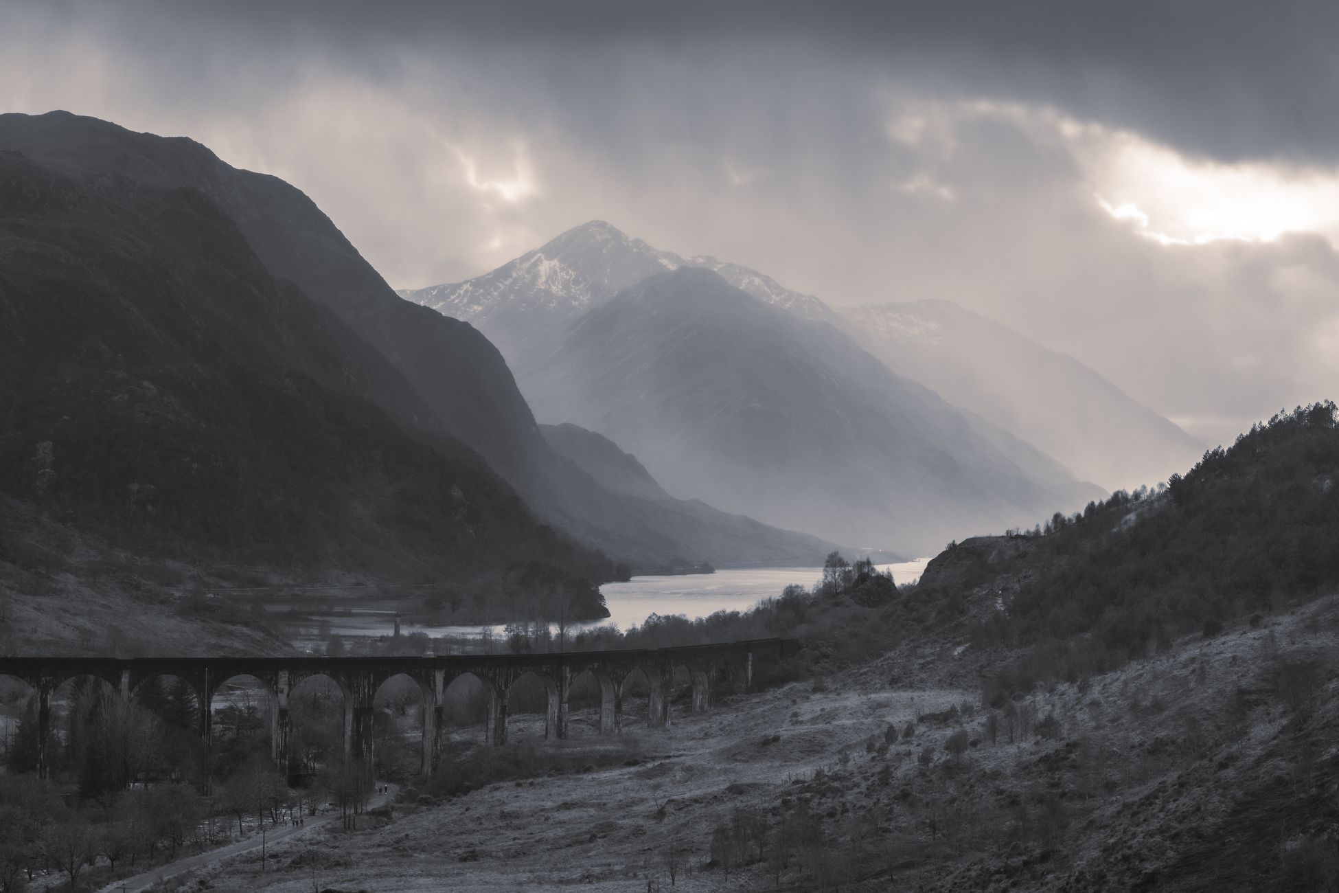 Stunning view of Glenfinnan Viaduct amidst the misty Scottish Highlands, showcasing serene landscapes.