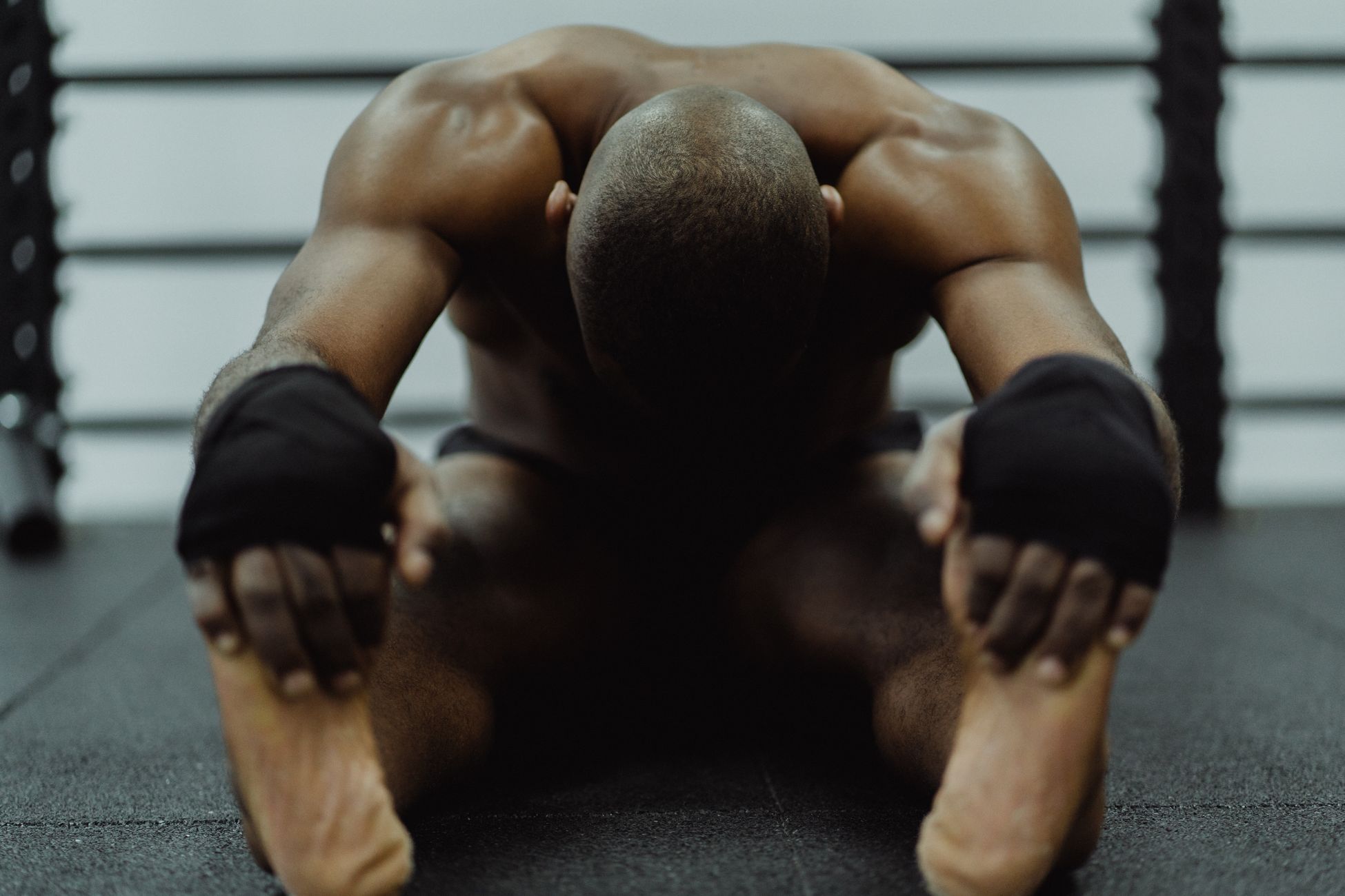 A man sitting on the floor of a gym, stretching to improve fitness and flexibility.