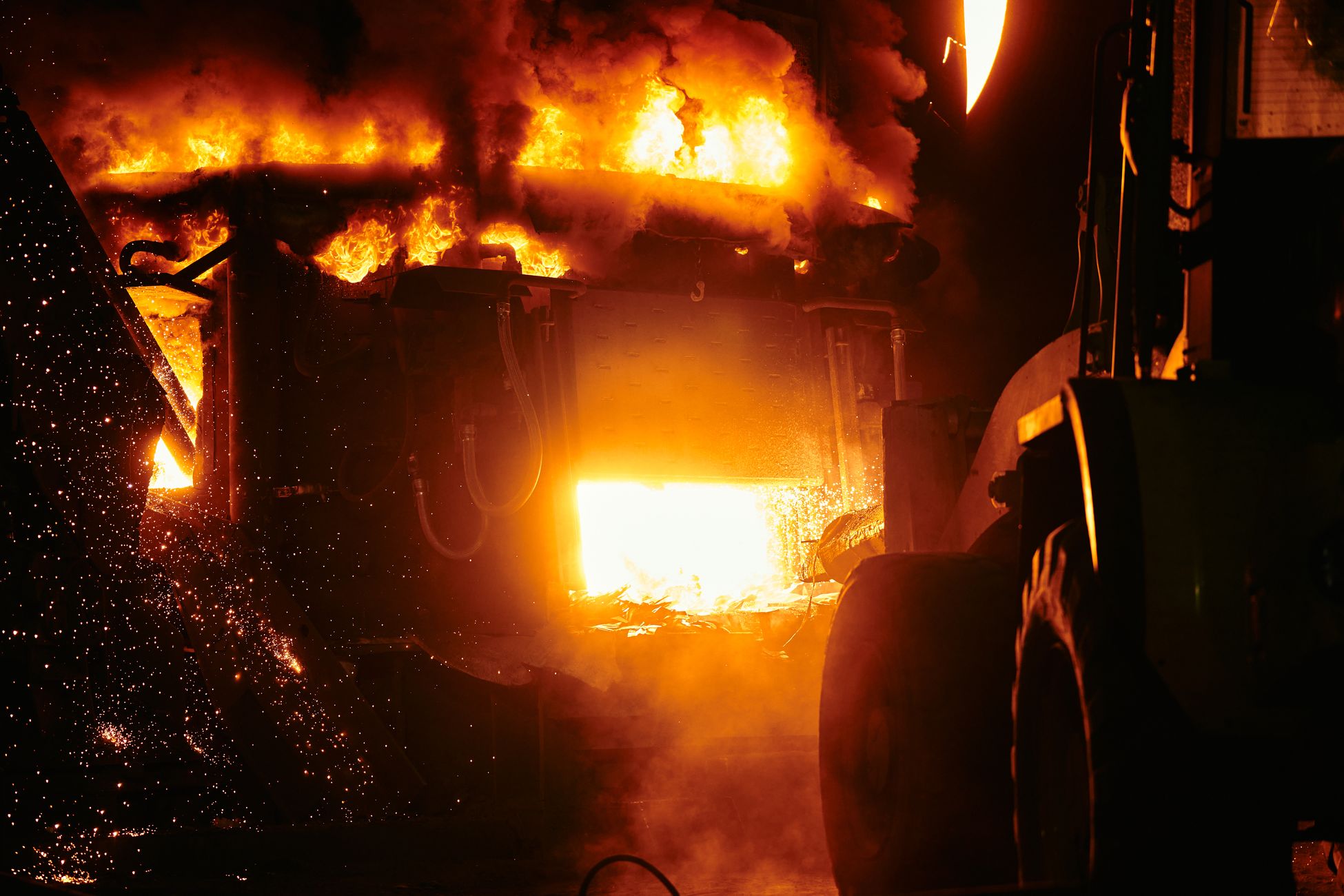 Close-up of a fiery furnace in an industrial setting emitting intense flames and sparks.