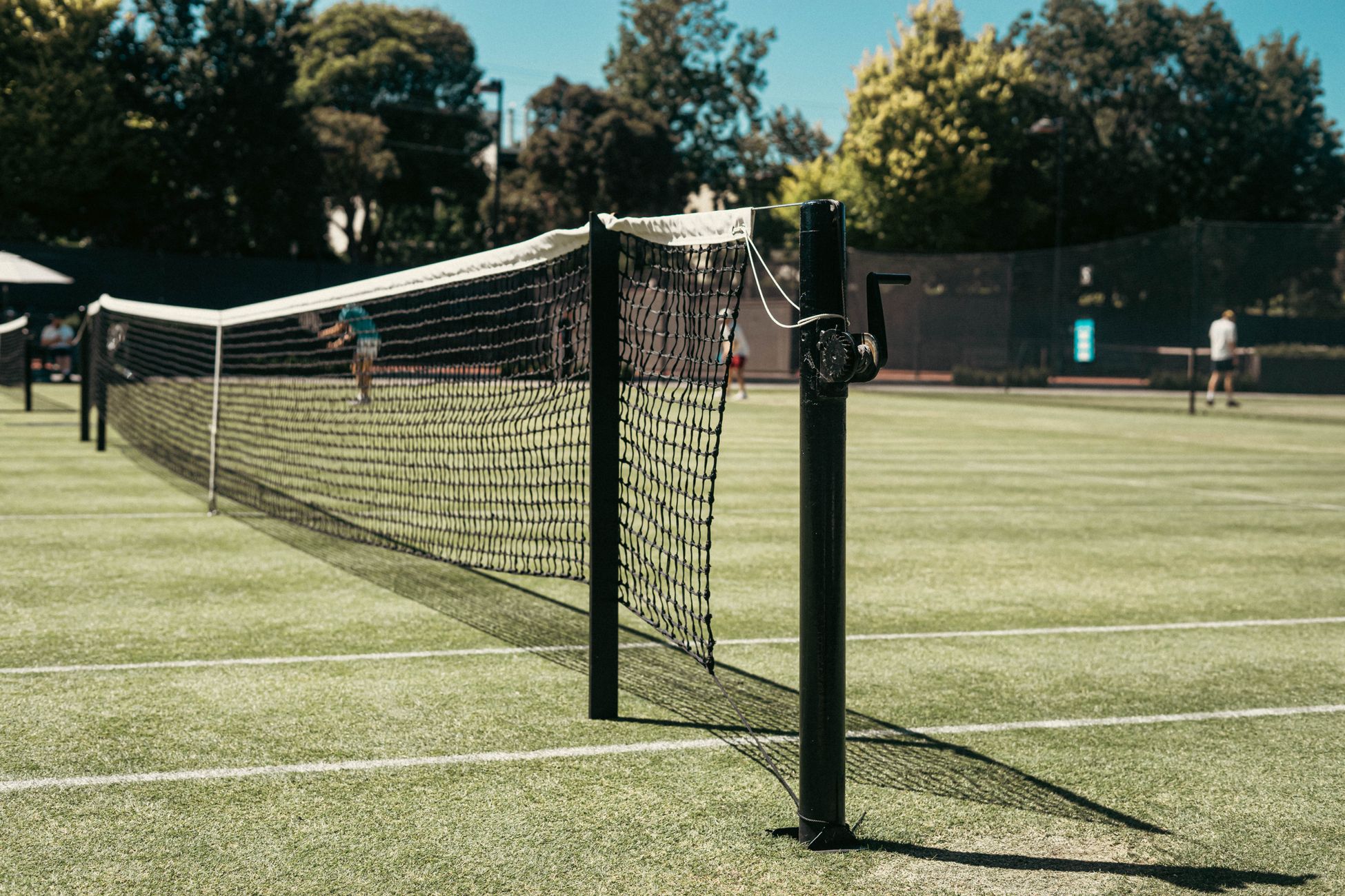 Grass tennis court with net at park in Melbourne, Australia. Perfect for leisure and sports enthusiasts.