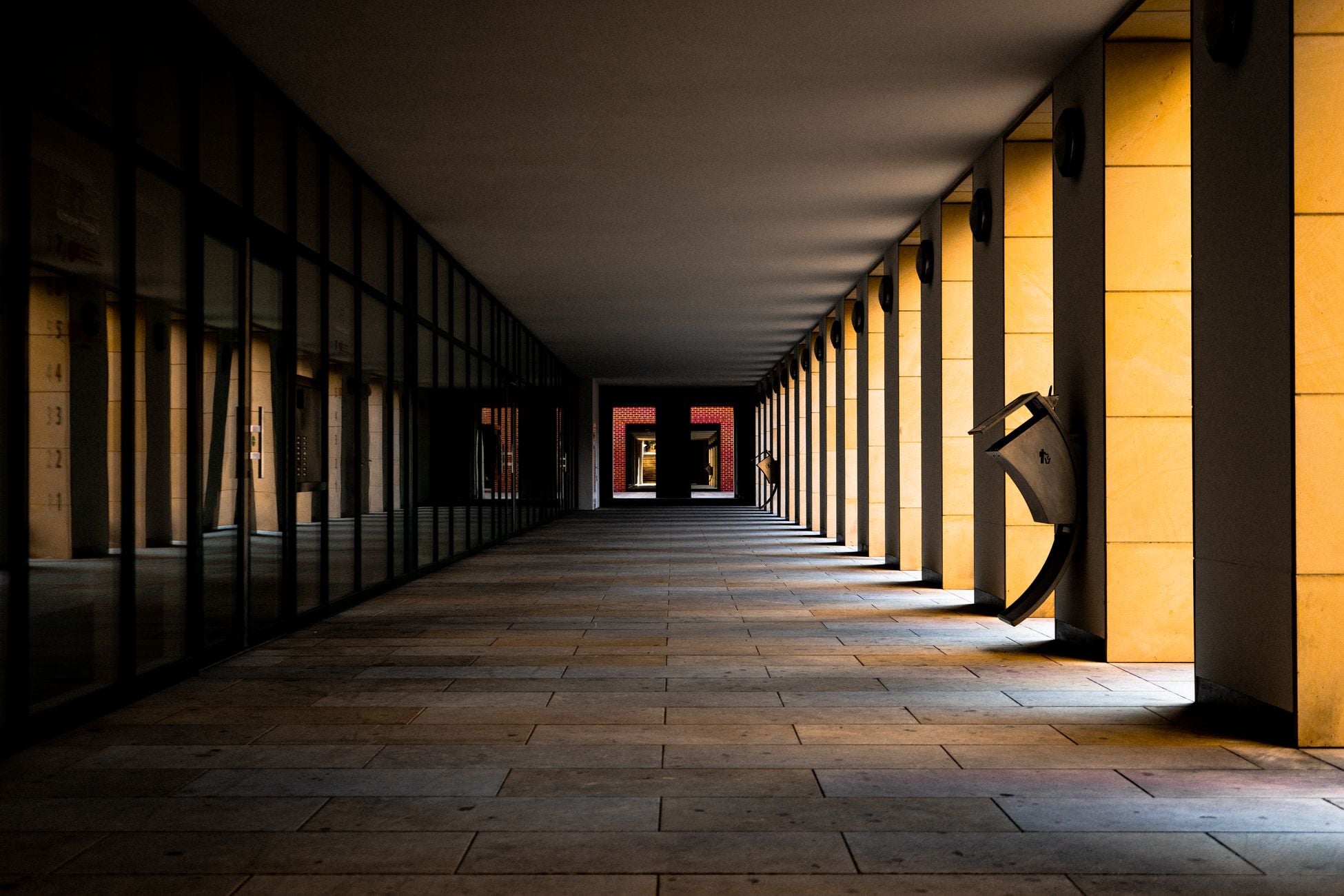 Dramatic view of an empty symmetrical corridor with striking golden columns casting shadows.