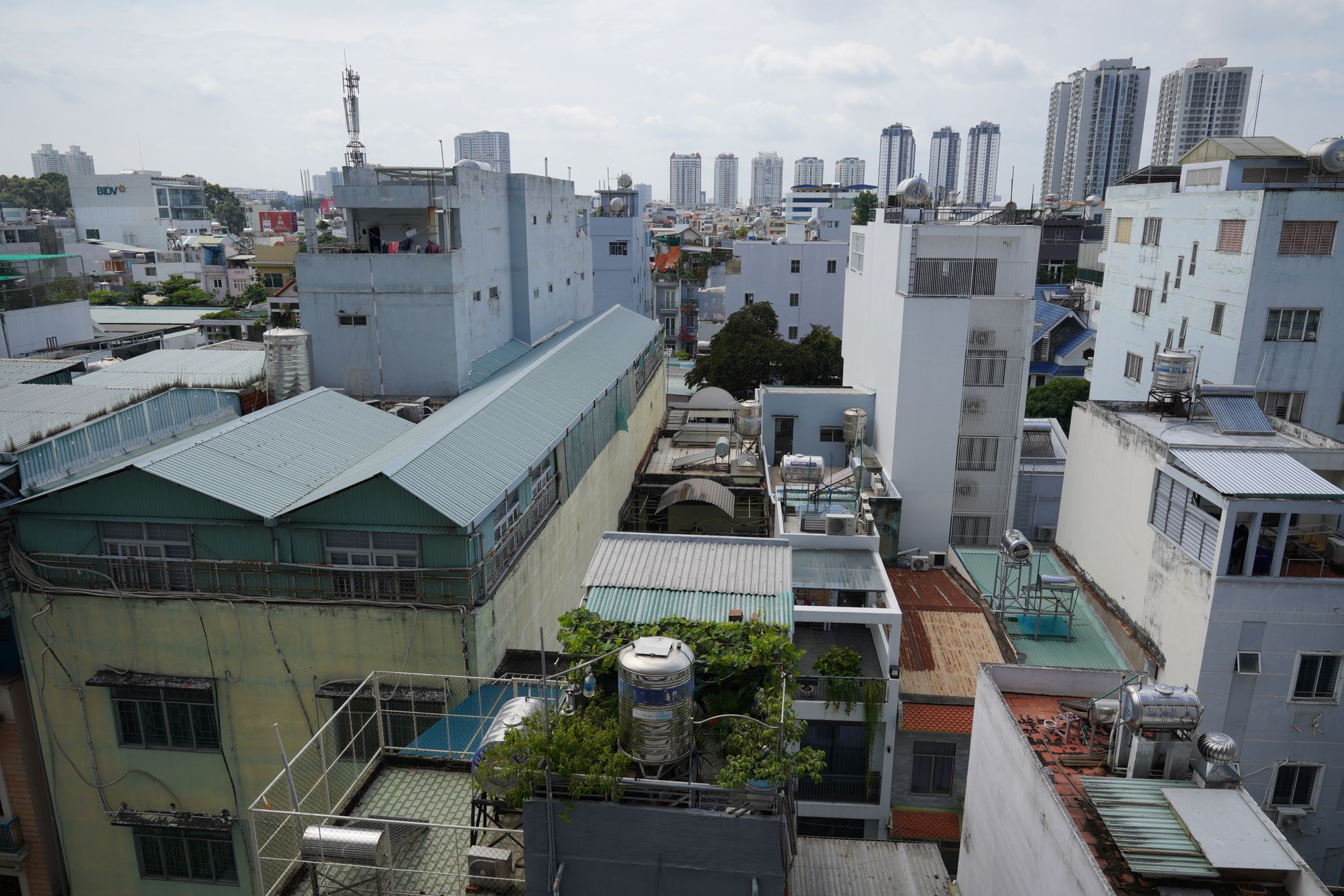 Aerial view of urban residential rooftops with high-rise buildings on the horizon.