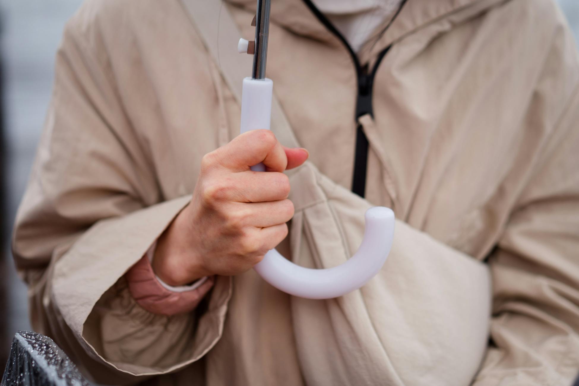 A detailed view of a person holding a white umbrella handle, emphasizing texture and color.