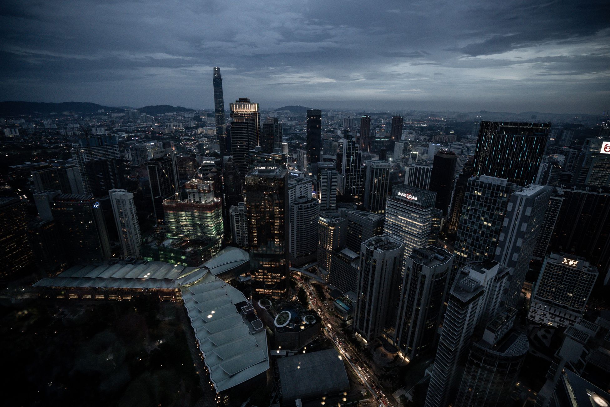 Aerial view of Kuala Lumpur's skyline, showcasing illuminated skyscrapers and urban landscape at night.