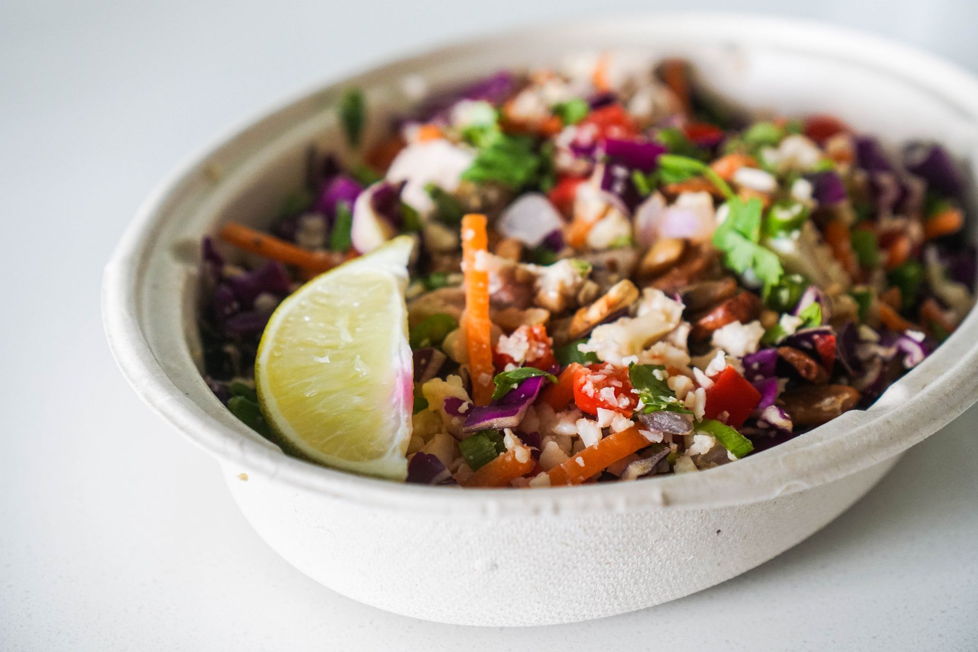Close-up of a colorful mixed vegetable salad garnished with lime in a bowl.