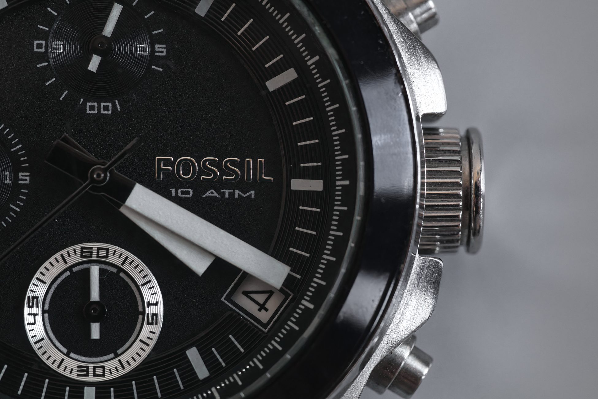 Detailed close-up of a Fossil wristwatch face with visible chronograph and date features.