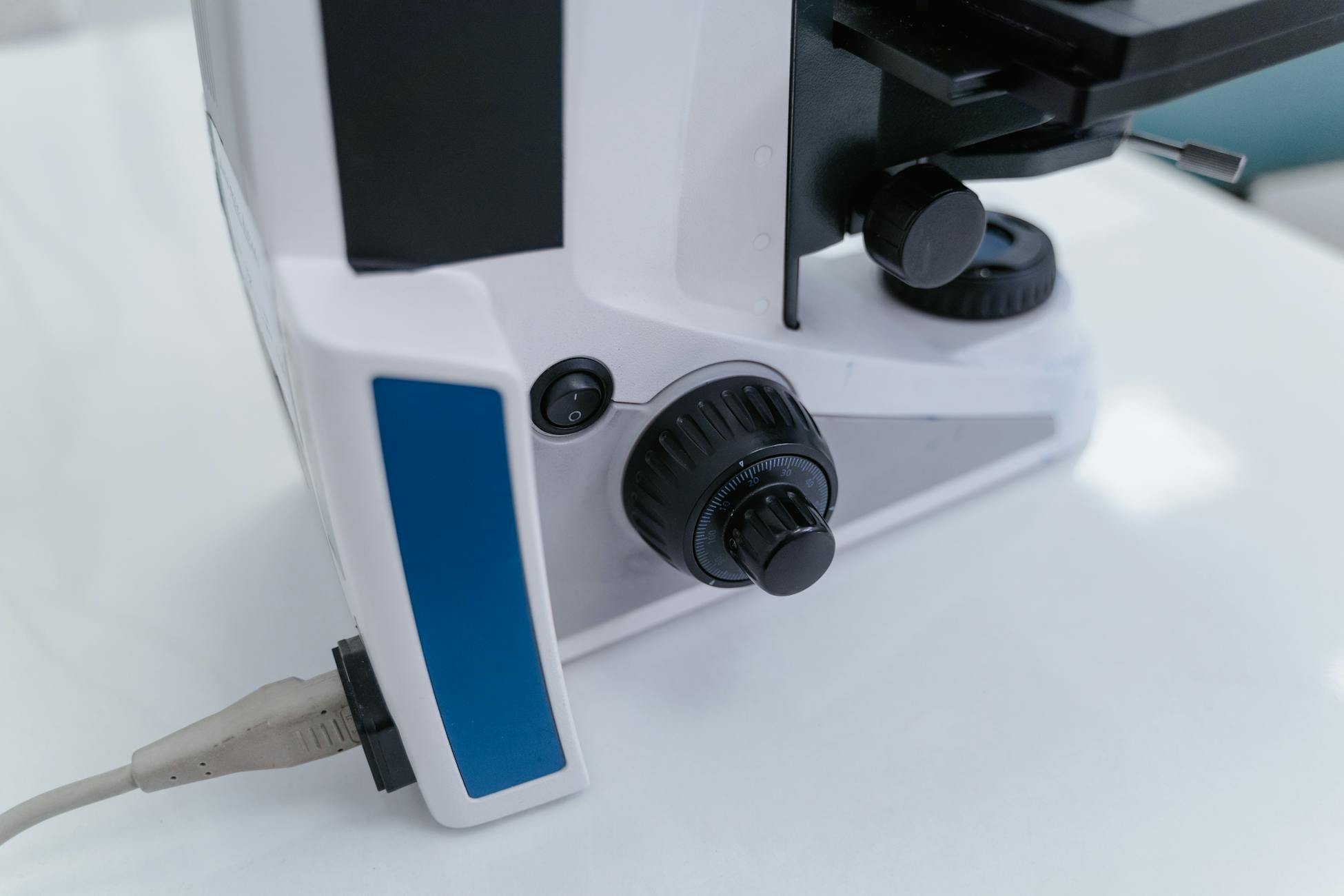 Detailed view of the adjustment controls on a laboratory microscope.