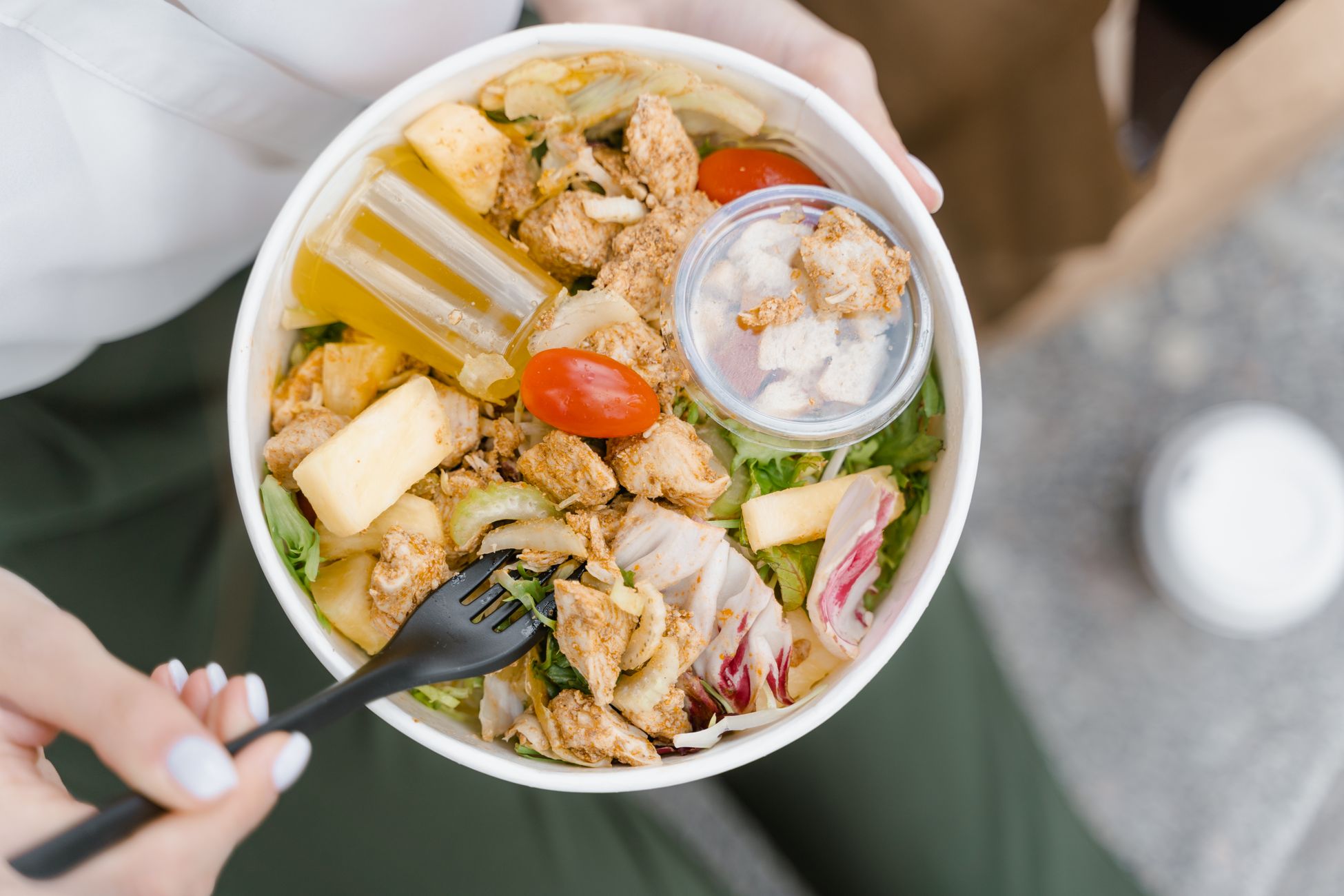 Top view of a delicious chicken salad bowl with fresh vegetables and dressing, perfect for a healthy meal.