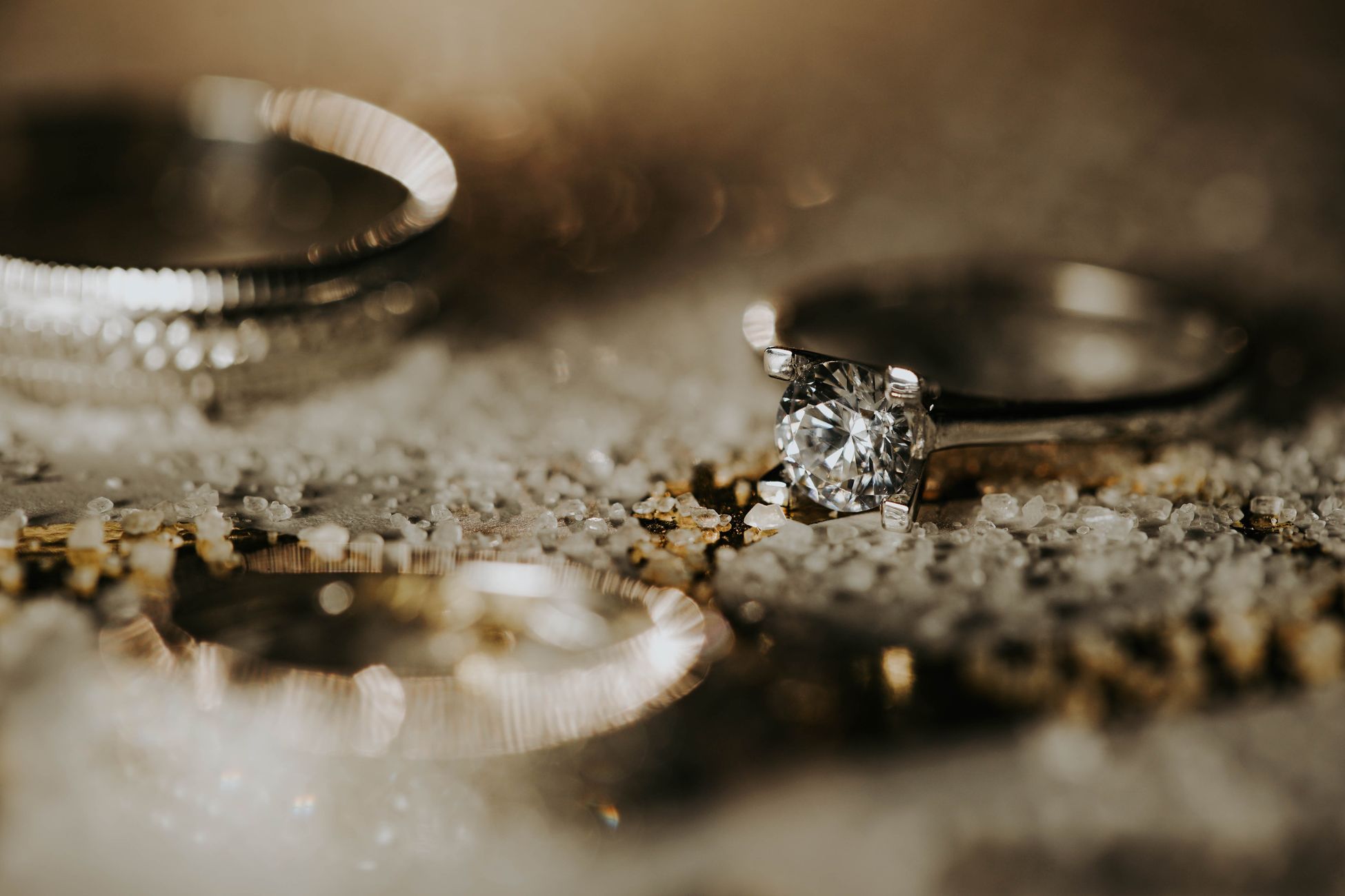 Close-up view of a silver engagement ring with a diamond centerpiece on a textured surface, exuding elegance.
