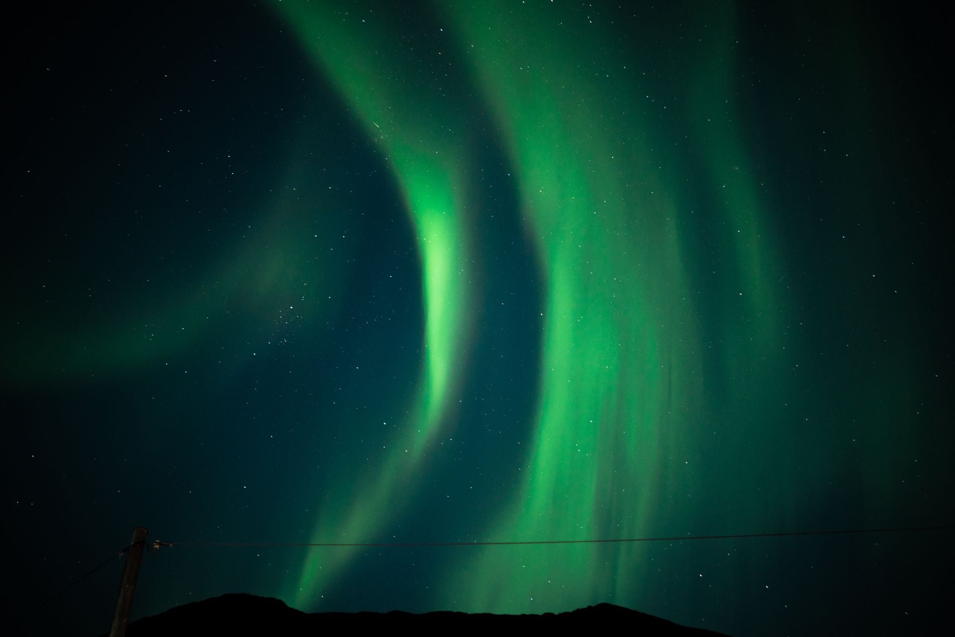Stunning green aurora borealis lighting up the night sky with stars.