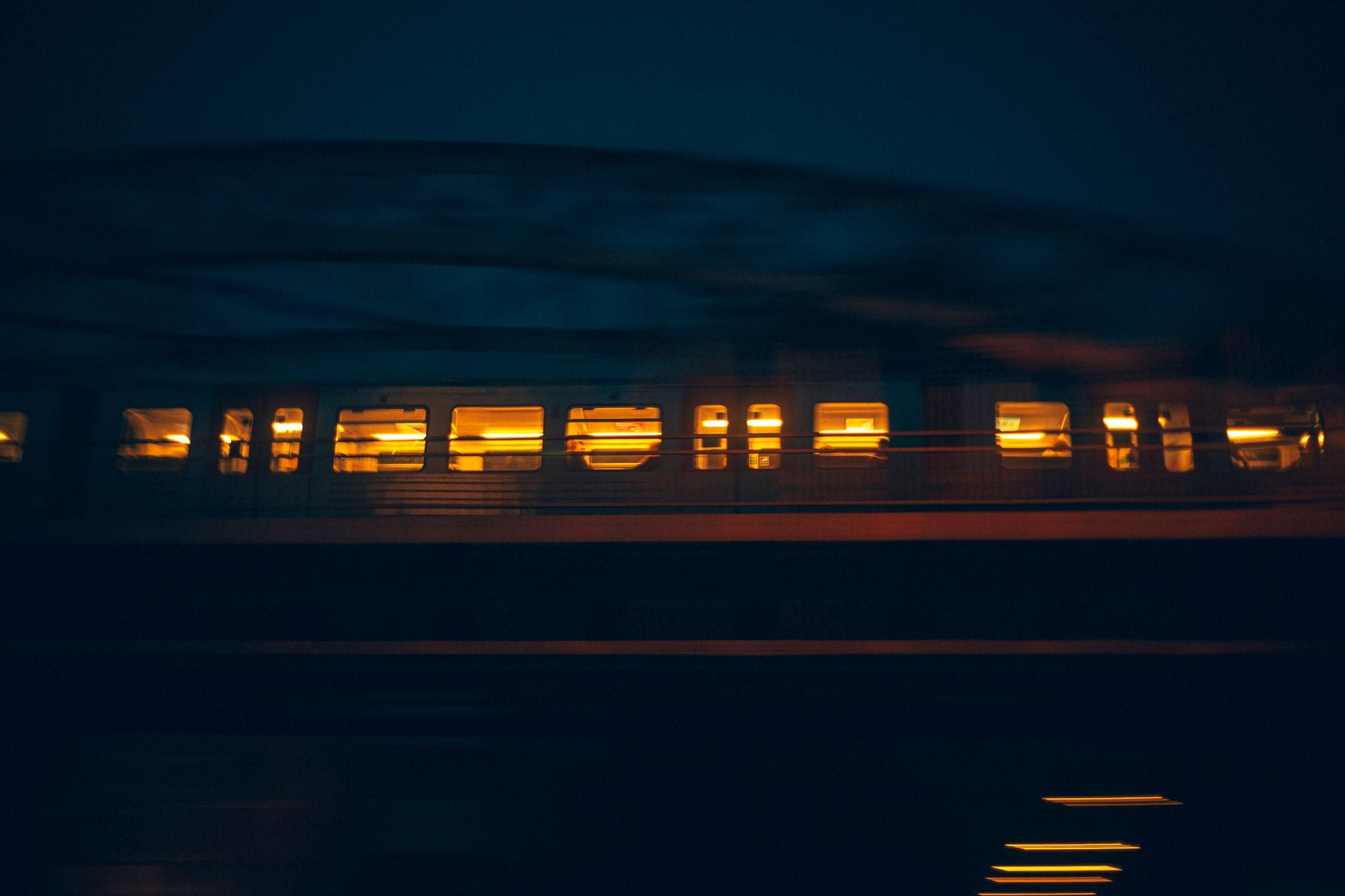 A moving train at night captured with motion blur, illuminating the cityscape of Hamburg.