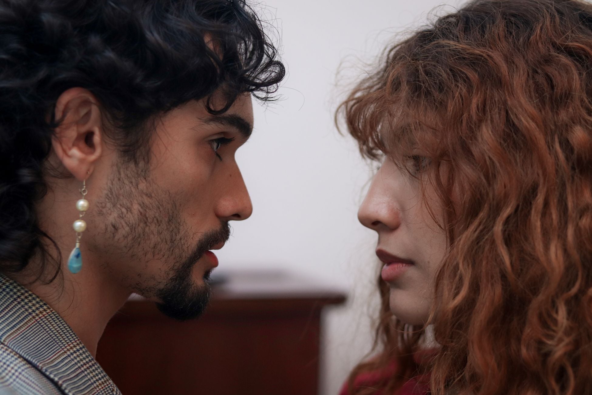 Intimate close-up portrait of two adults facing each other indoors with soft lighting.