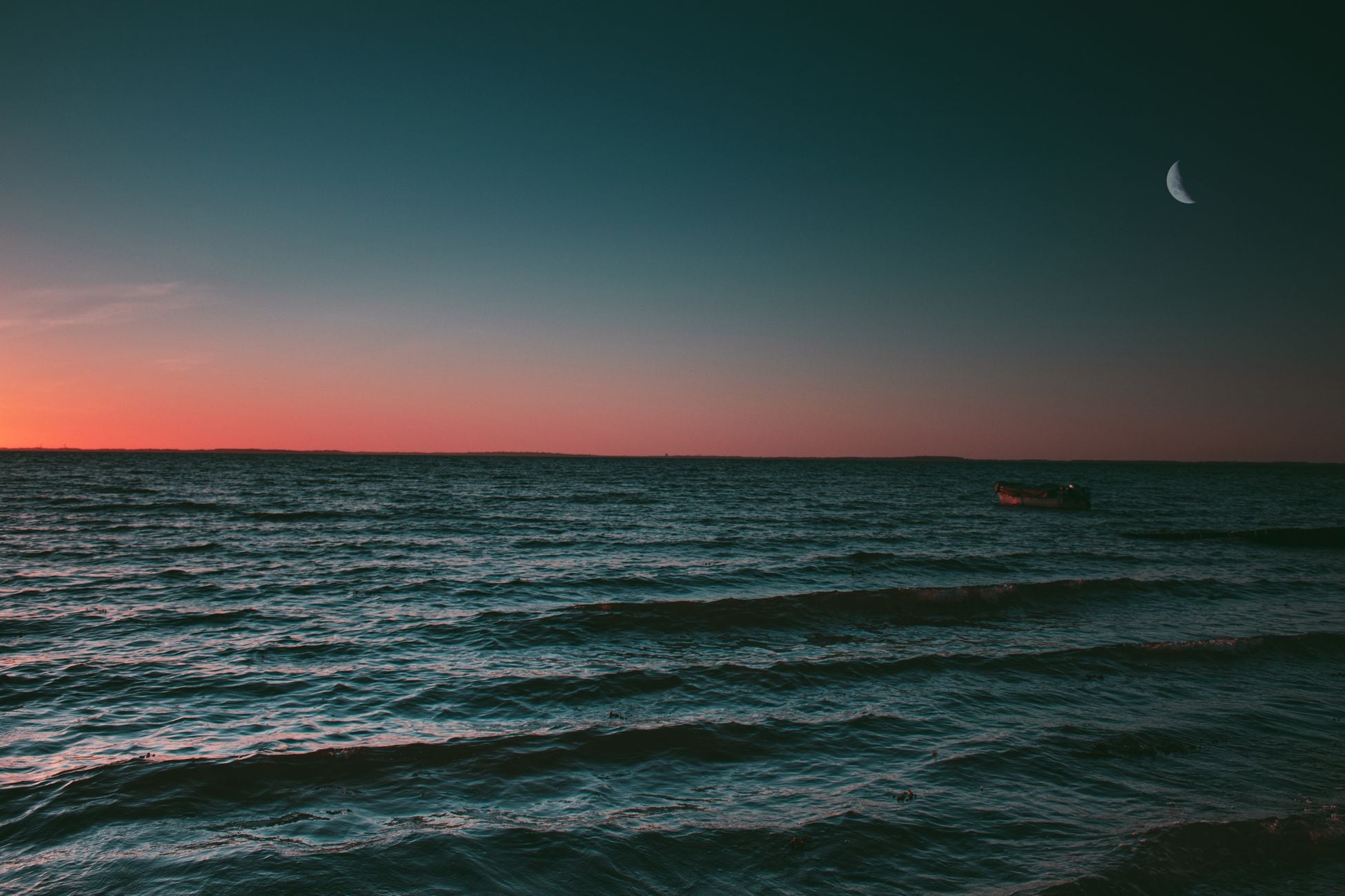Beautiful sunset view of the Baltic Sea with a crescent moon and gentle waves creating a tranquil seascape.