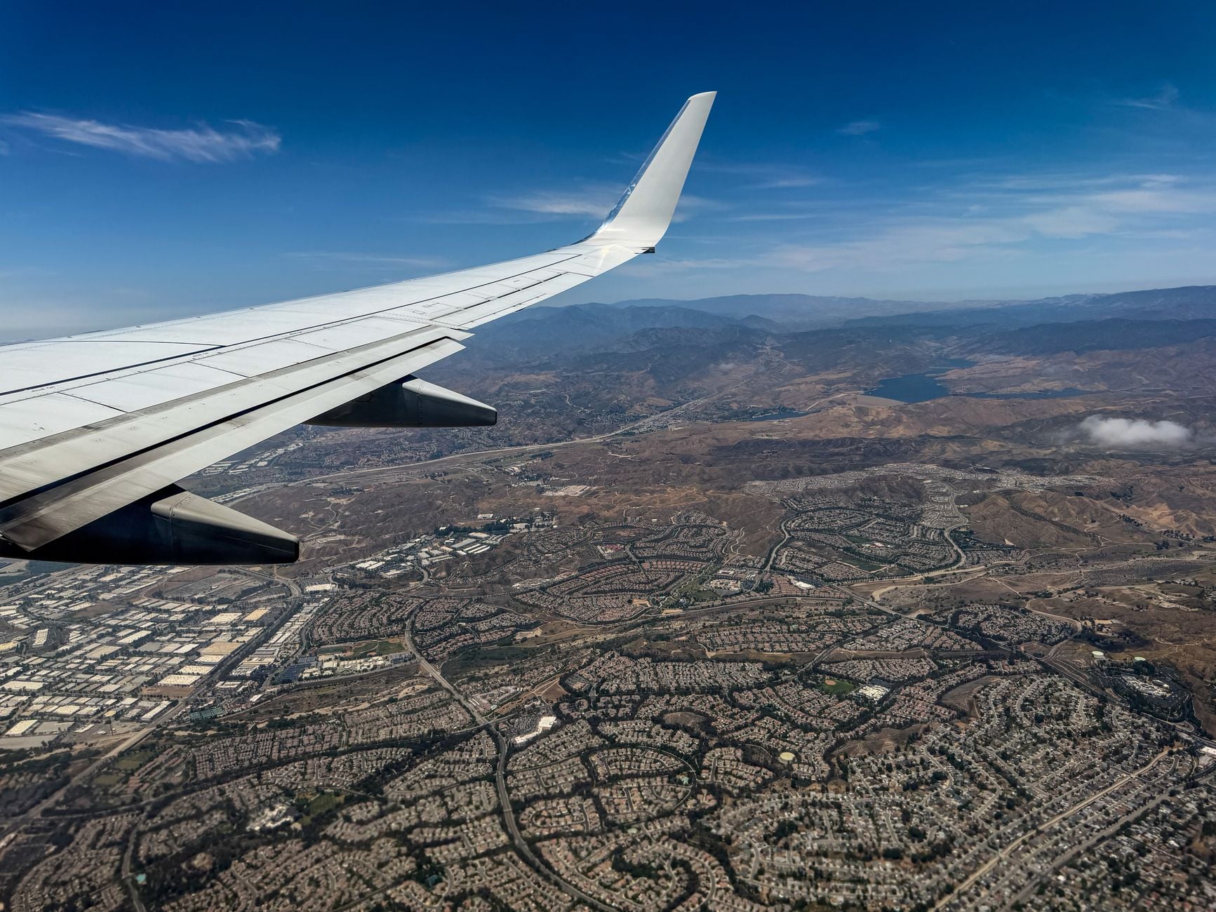 Vista aérea panorâmica de uma extensa paisagem urbana capturada da janela de um avião em vôo.