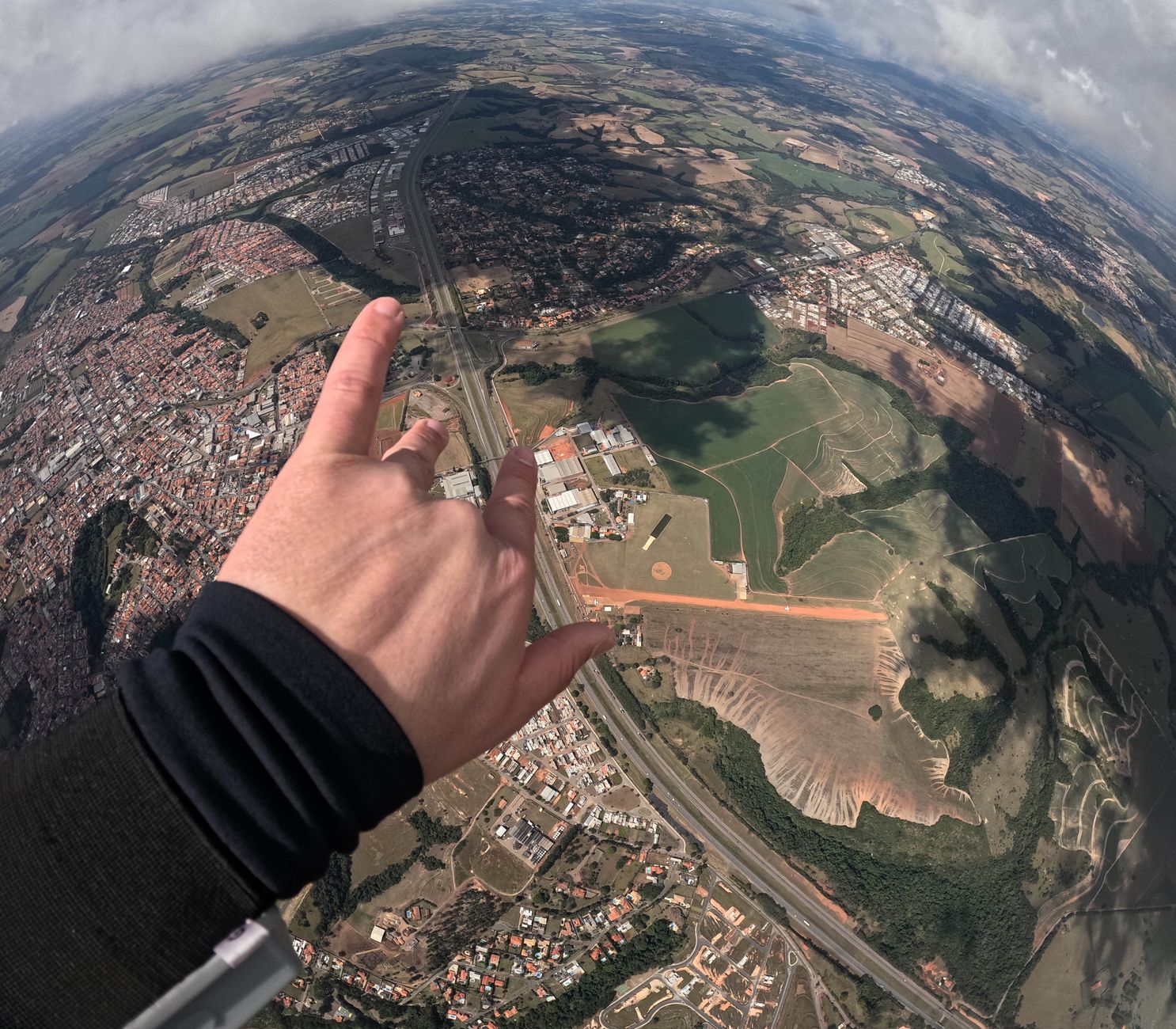 Aerial view of sprawling landscape with a hand making a gesture in the foreground.