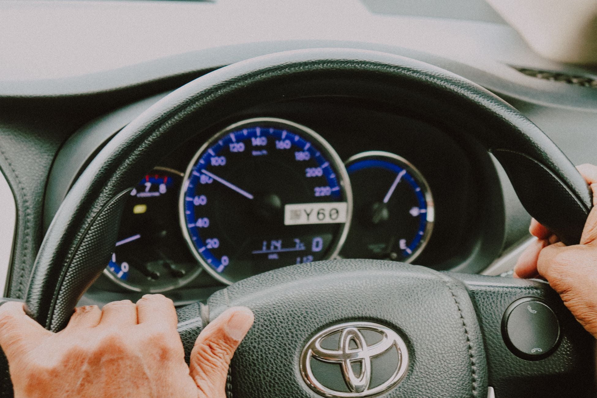 Hands resting on a car steering wheel.