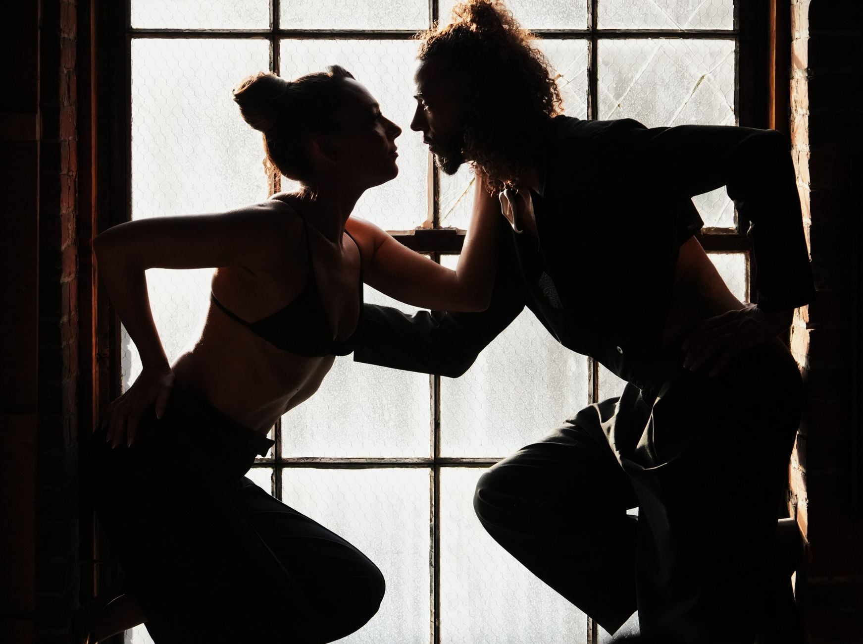 Dramatic silhouette of a couple near a window, showcasing intimacy and shadow play.