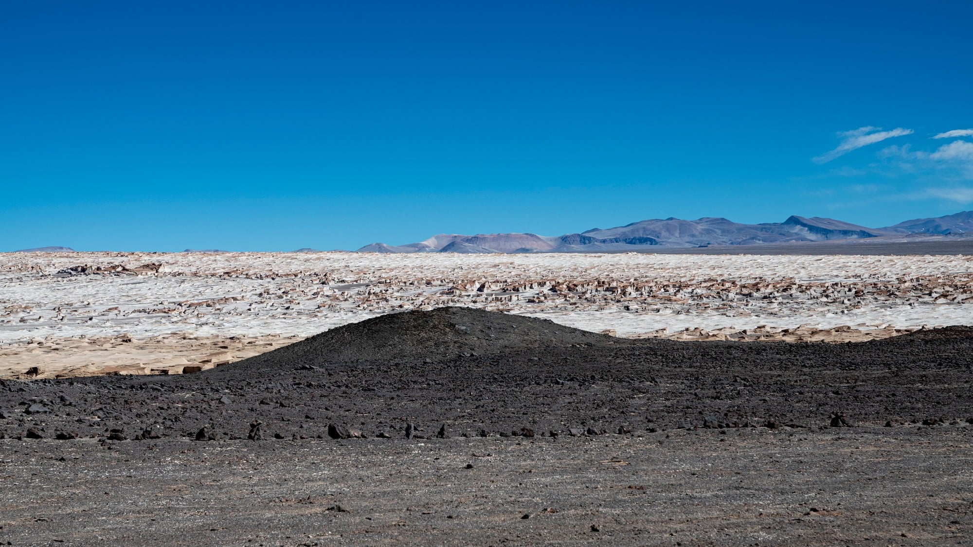 Dark volcanic terrain beside bright salt flats in Chile's Atacama Desert