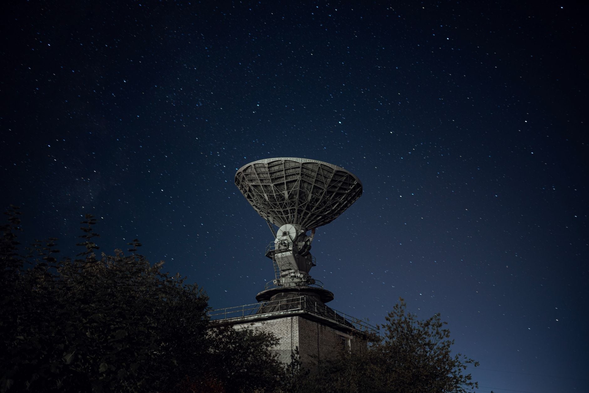 A large steerable radio antenna beneath a star-filled night sky