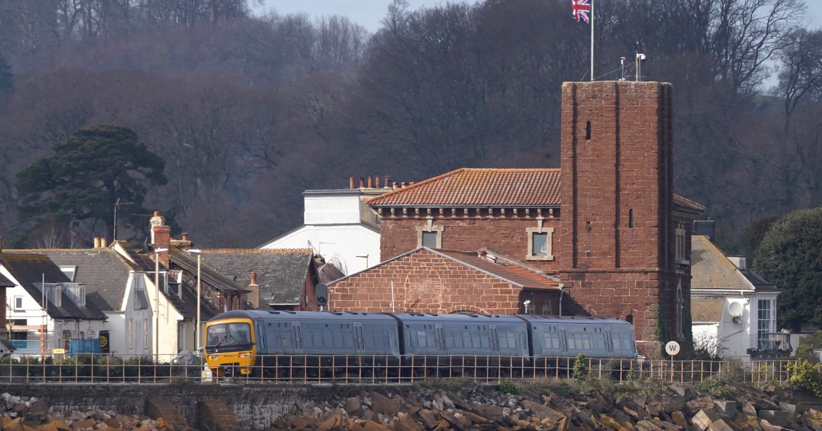 A train passes the tall stone pumping house built for Brunel-s atmospheric railway at Starcross, on the west bank of the River Exe in Devon