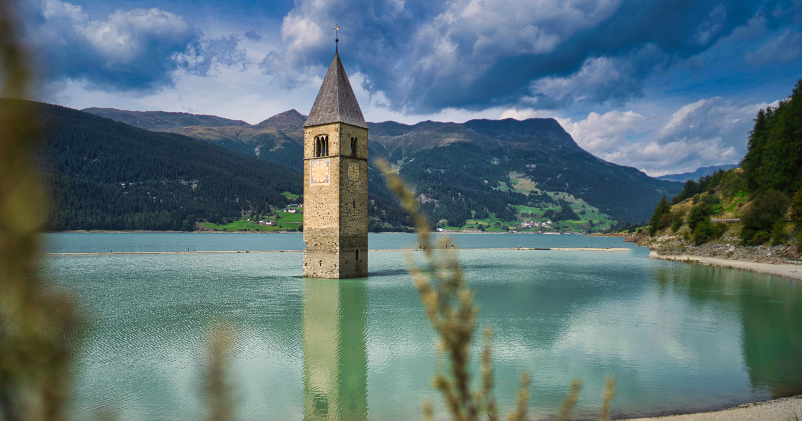 The Italian village of Curon was deliberately flooded in 1950 to build a reservoir, drowning the old town under the water, and to this day the bell tower of its submerged 14th-century church still rises alone out of the lake, the only part of a village that otherwise exists only underwater.